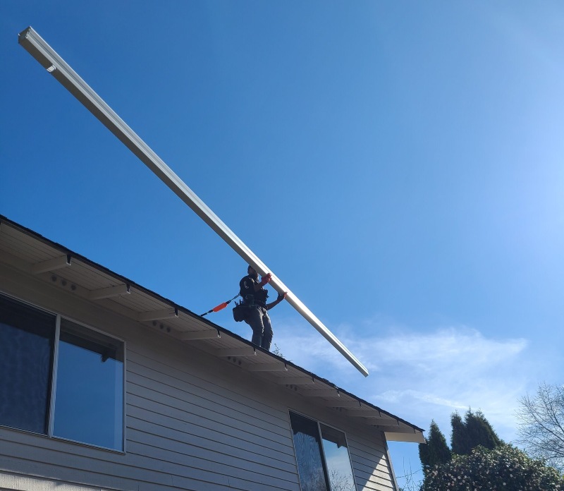 A gutter specialist installs replacement gutters on a home in Seattle, WA.