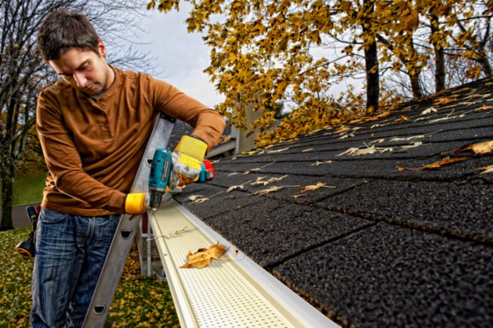 The man fixing gutter in top of the house