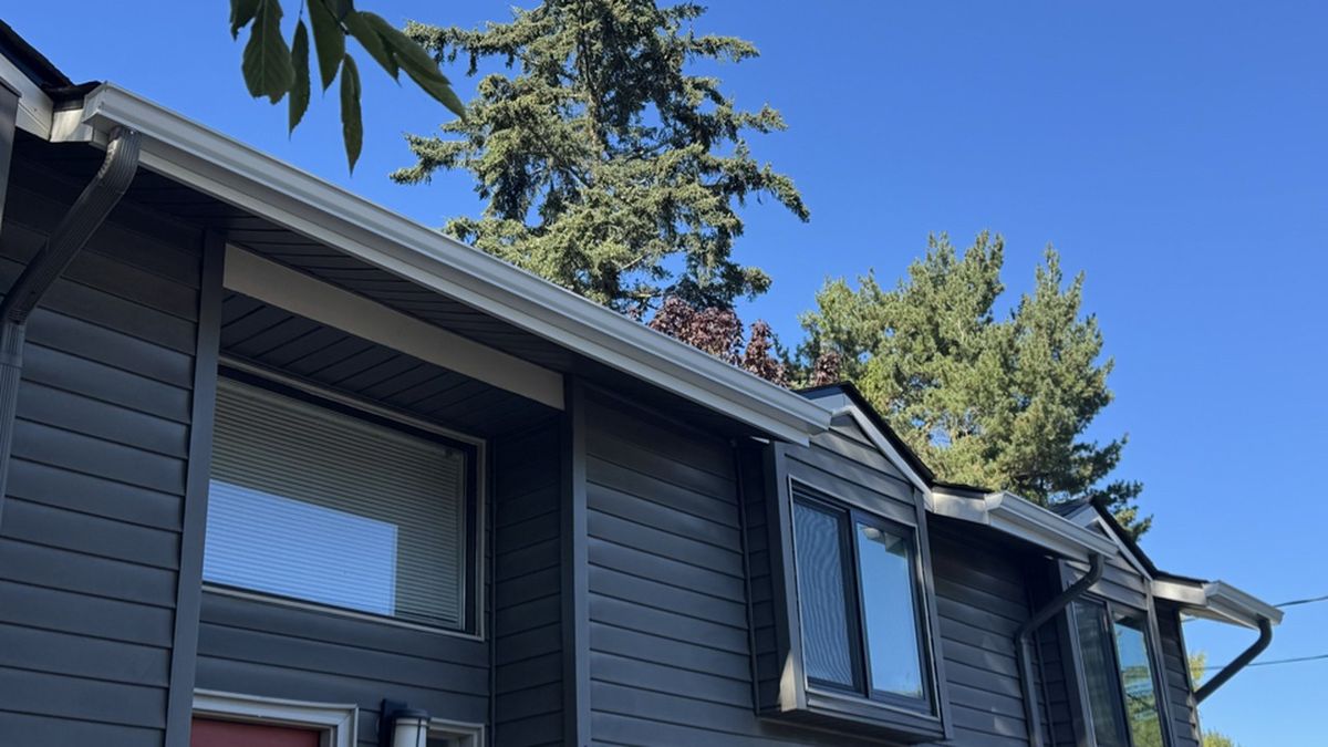 After: new seamless white gutters on rebuilt fascia along the same Seattle roofline