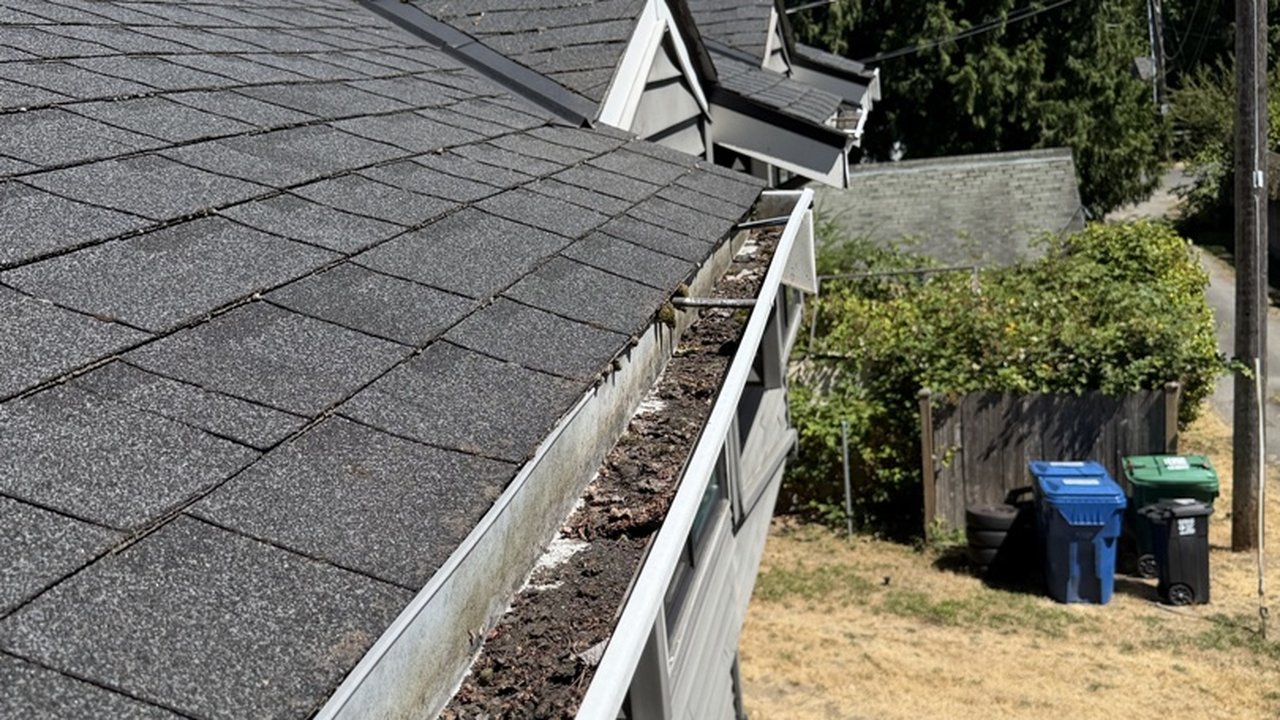 Before: gutter packed with debris and pulling away from the roofline of a Seattle home